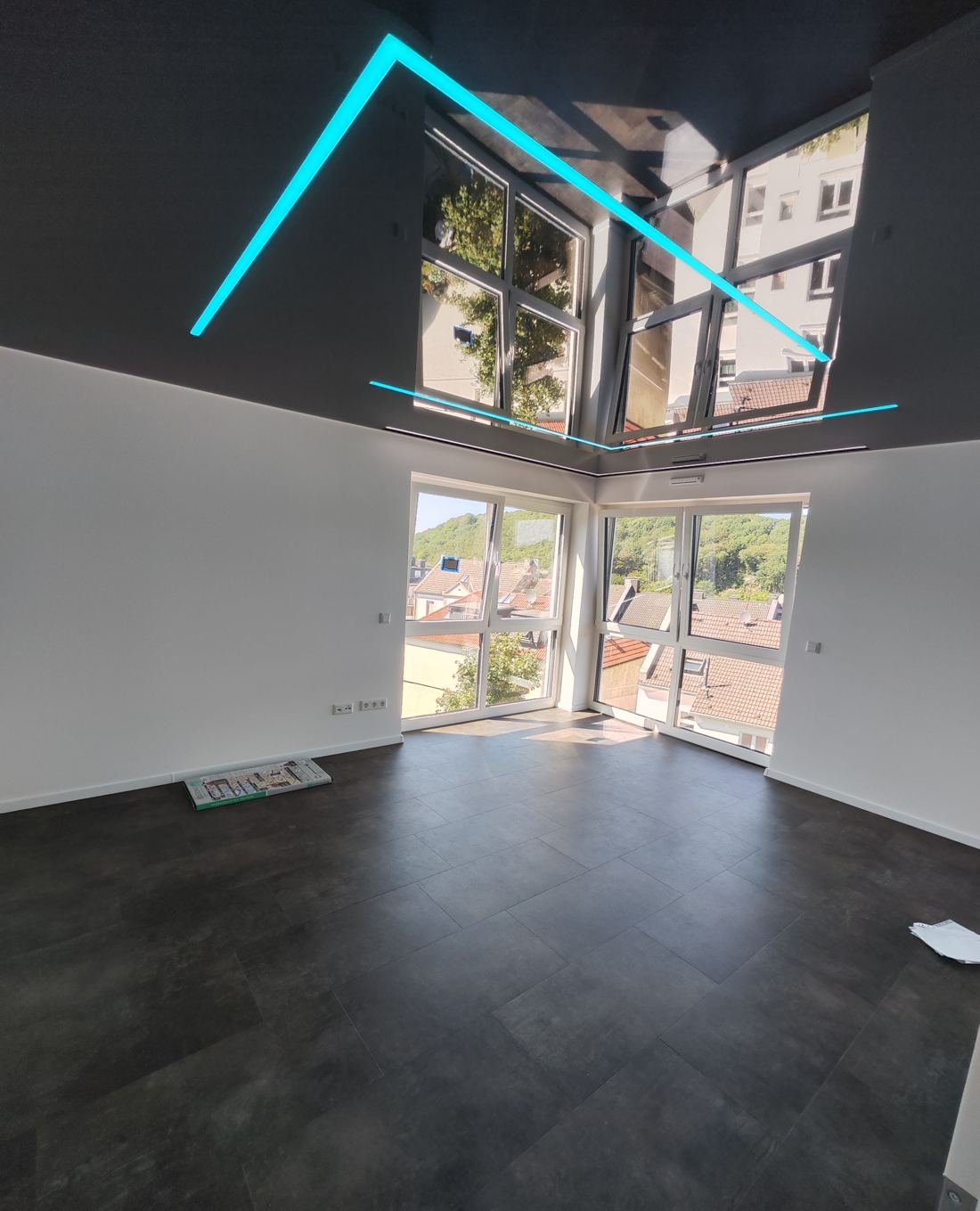 Glanzdecke mit türkisfarbener LED-Linie, in der sich die Fenster spiegeln