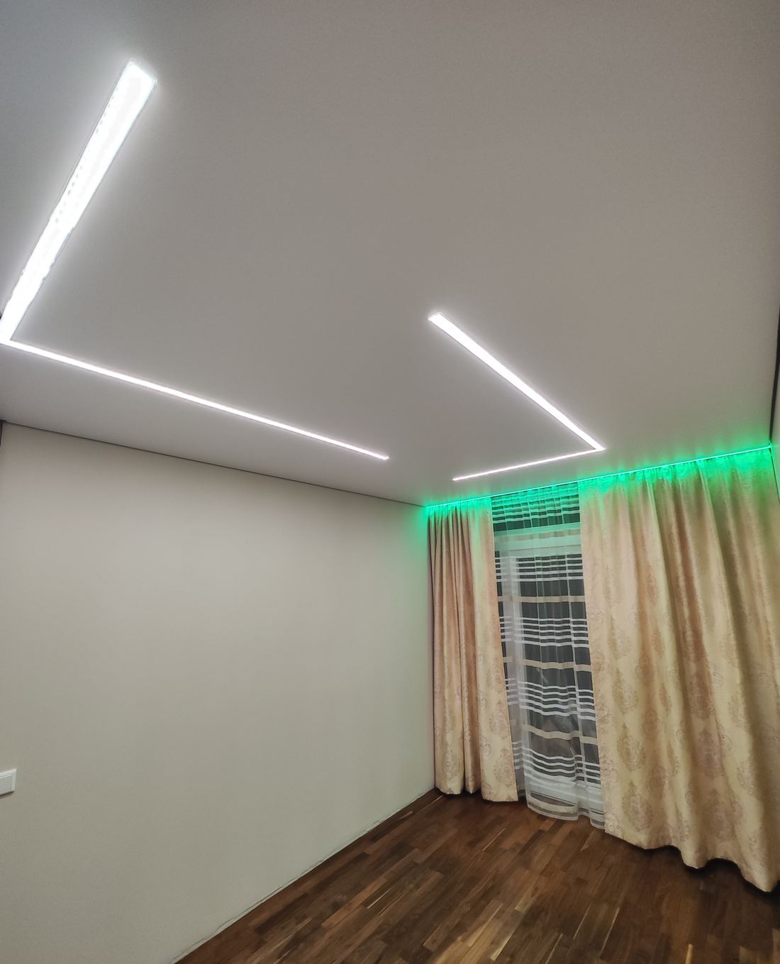 Zimmer mit weißen Lichtlinien und grüner Vorhangbeleuchtung