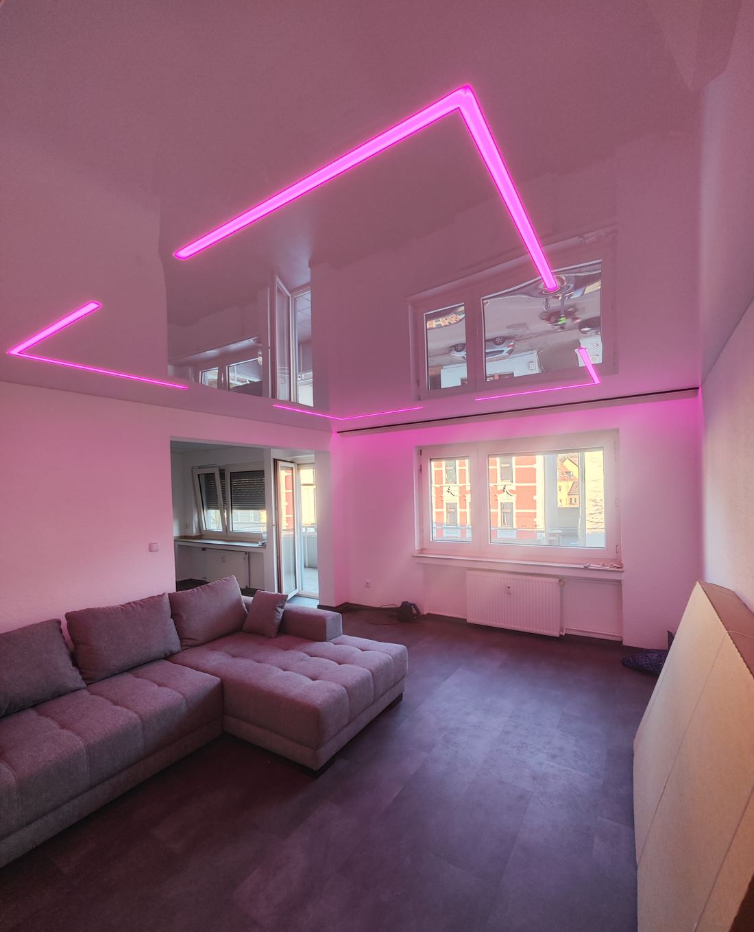 Wohnzimmer mit Glanzdecke und pinkfarbenen RGB-Lichtlinien