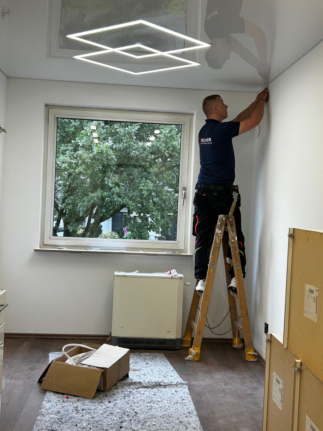 Monteur beim Spannen einer Decke mit Lichtrahmen