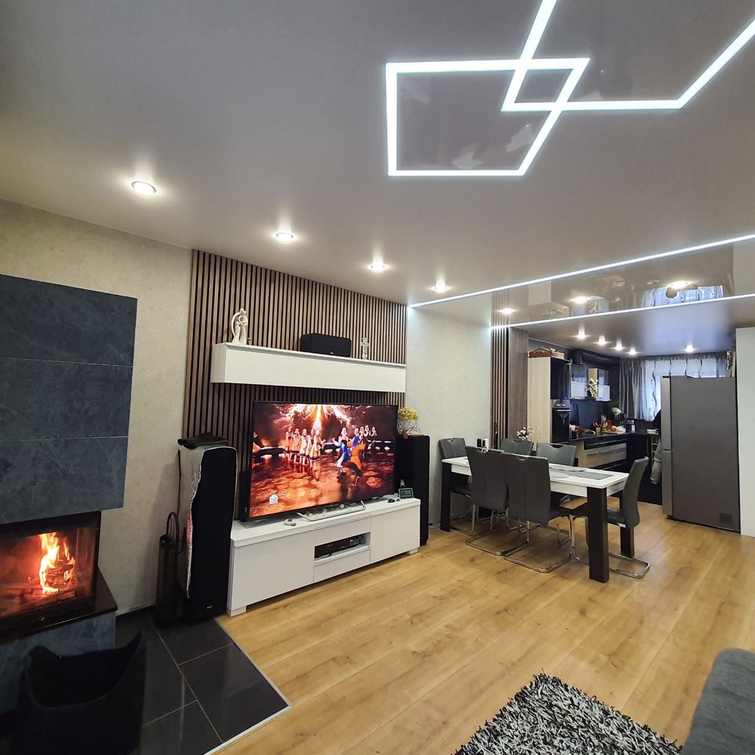 Wohnzimmer mit Kamin, Glanzdecke, Lichtlinien und Einbaustrahlern